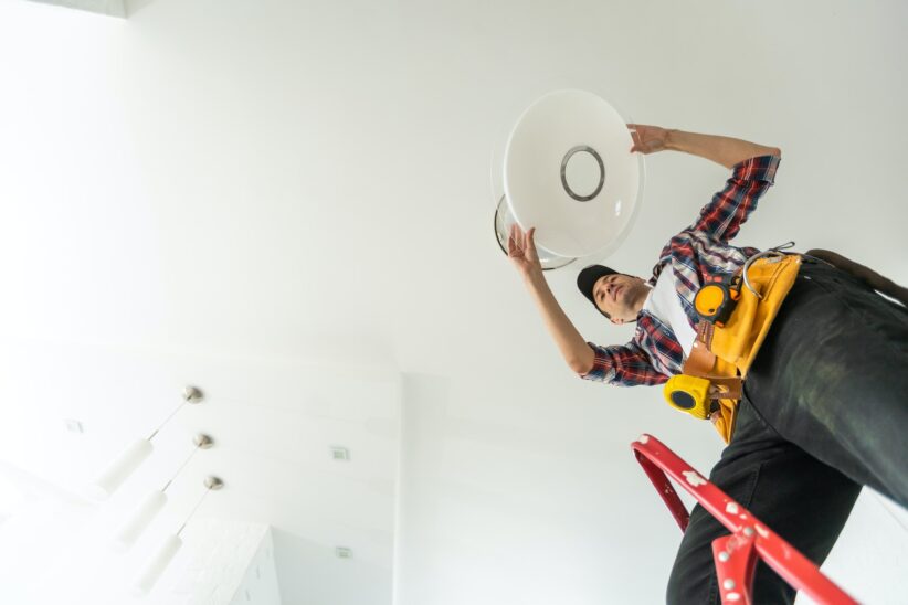 electrician installing led light bulbs in ceiling lamp
